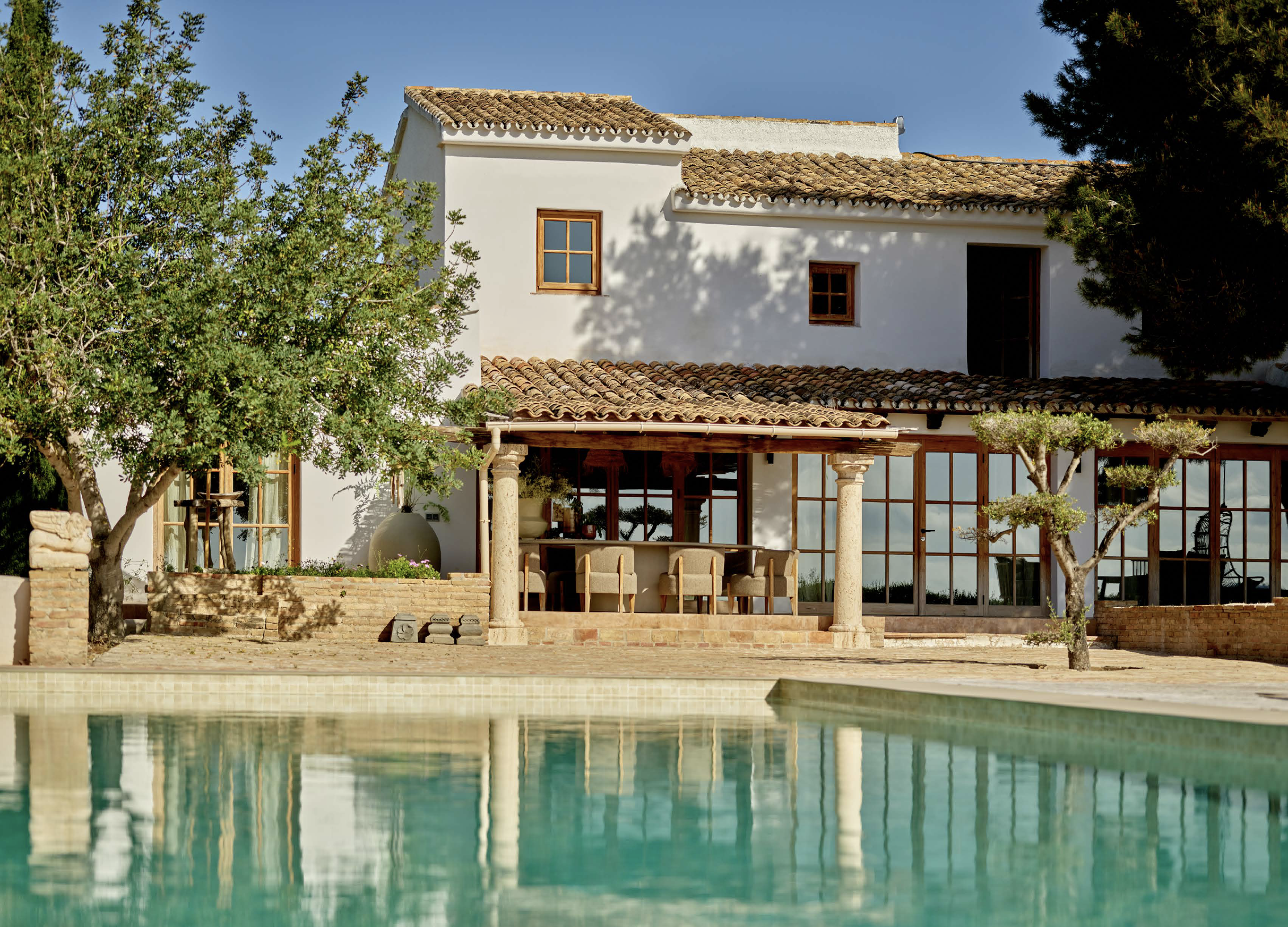 Spanish wellness retreat villa and pool, framed by trees.